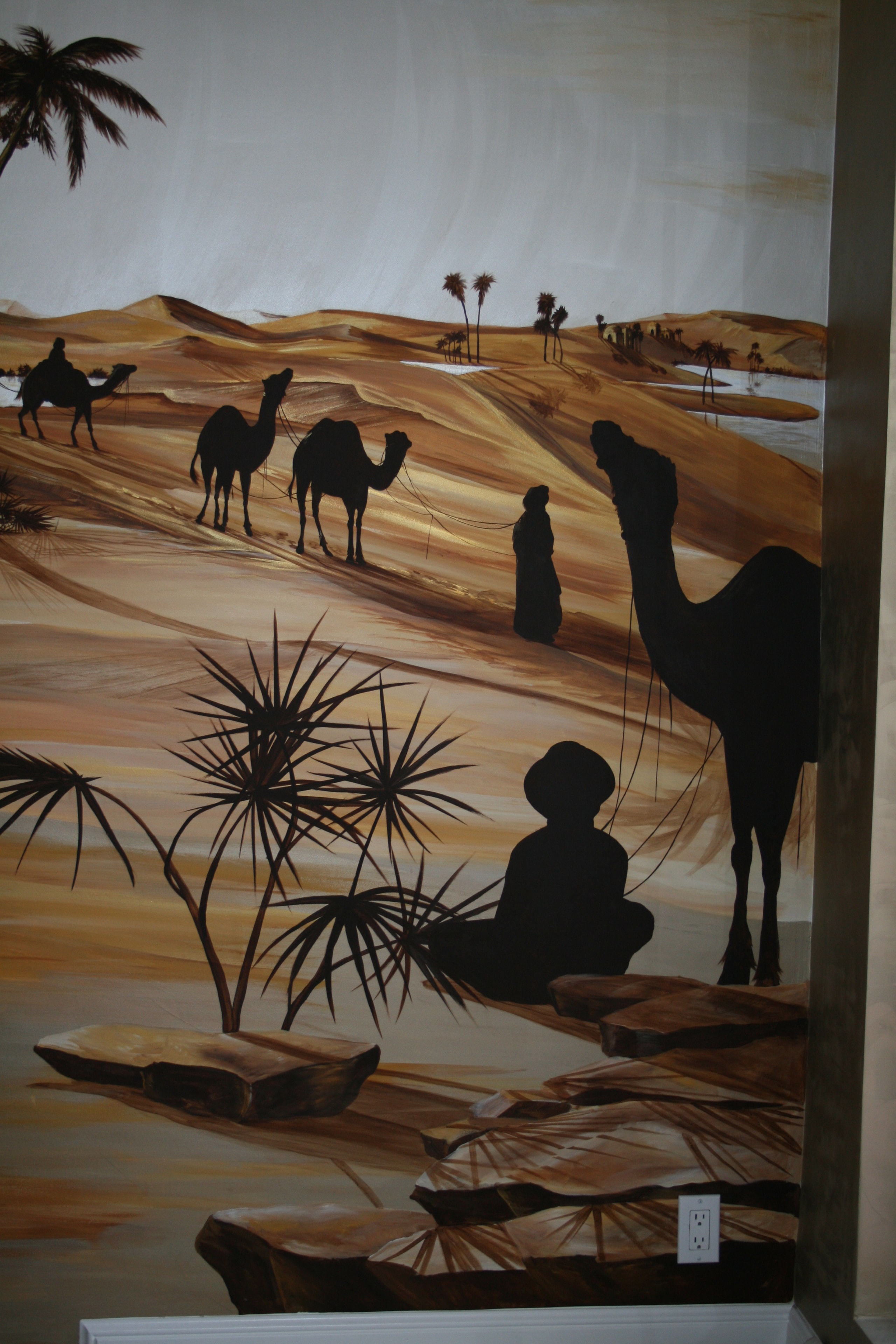 Sahara desert mural — camel caravan detail with seated figure and palm trees