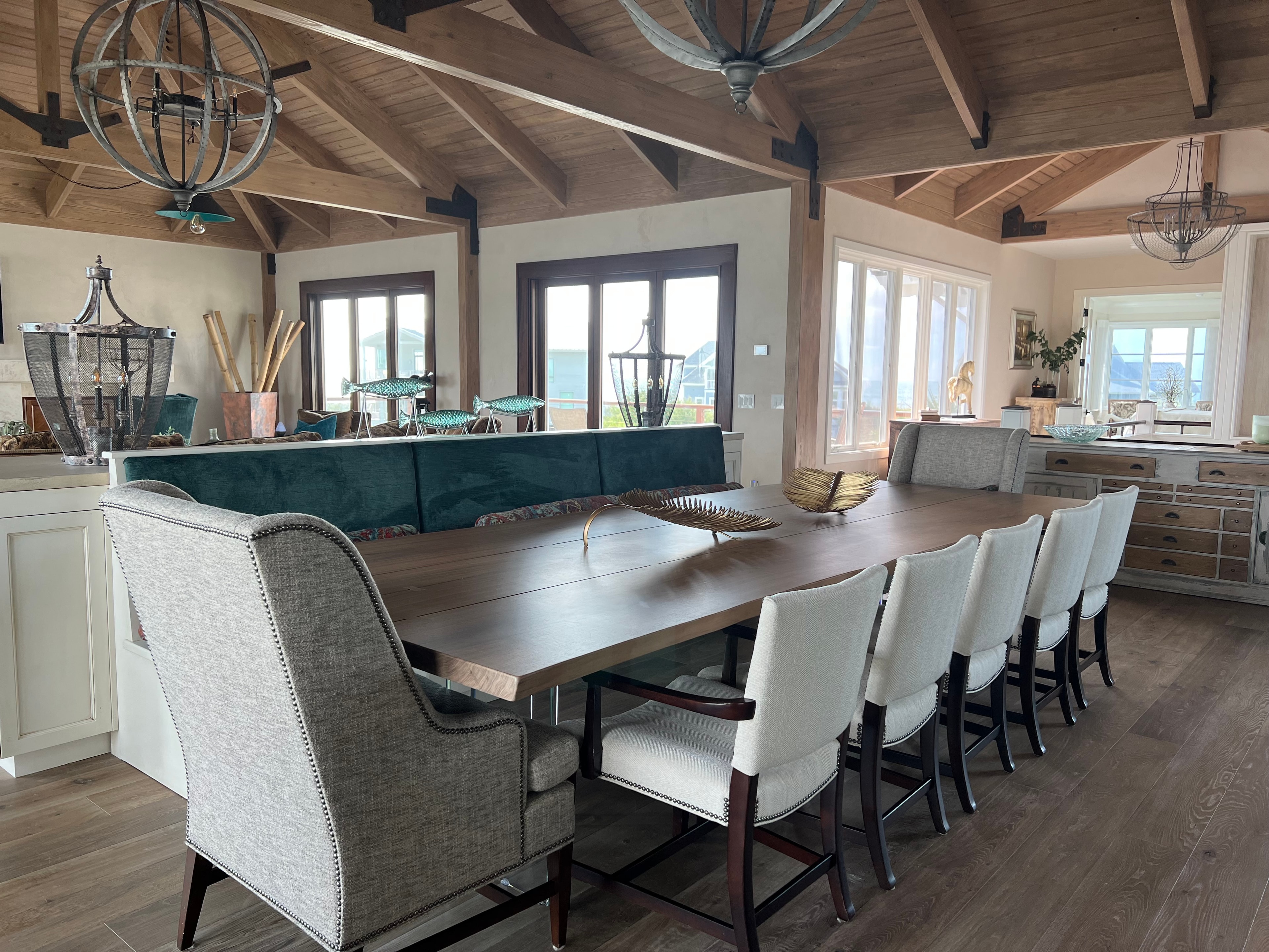 Figure Eight Island — dining room with timber ceiling, orb chandeliers, and teal banquette