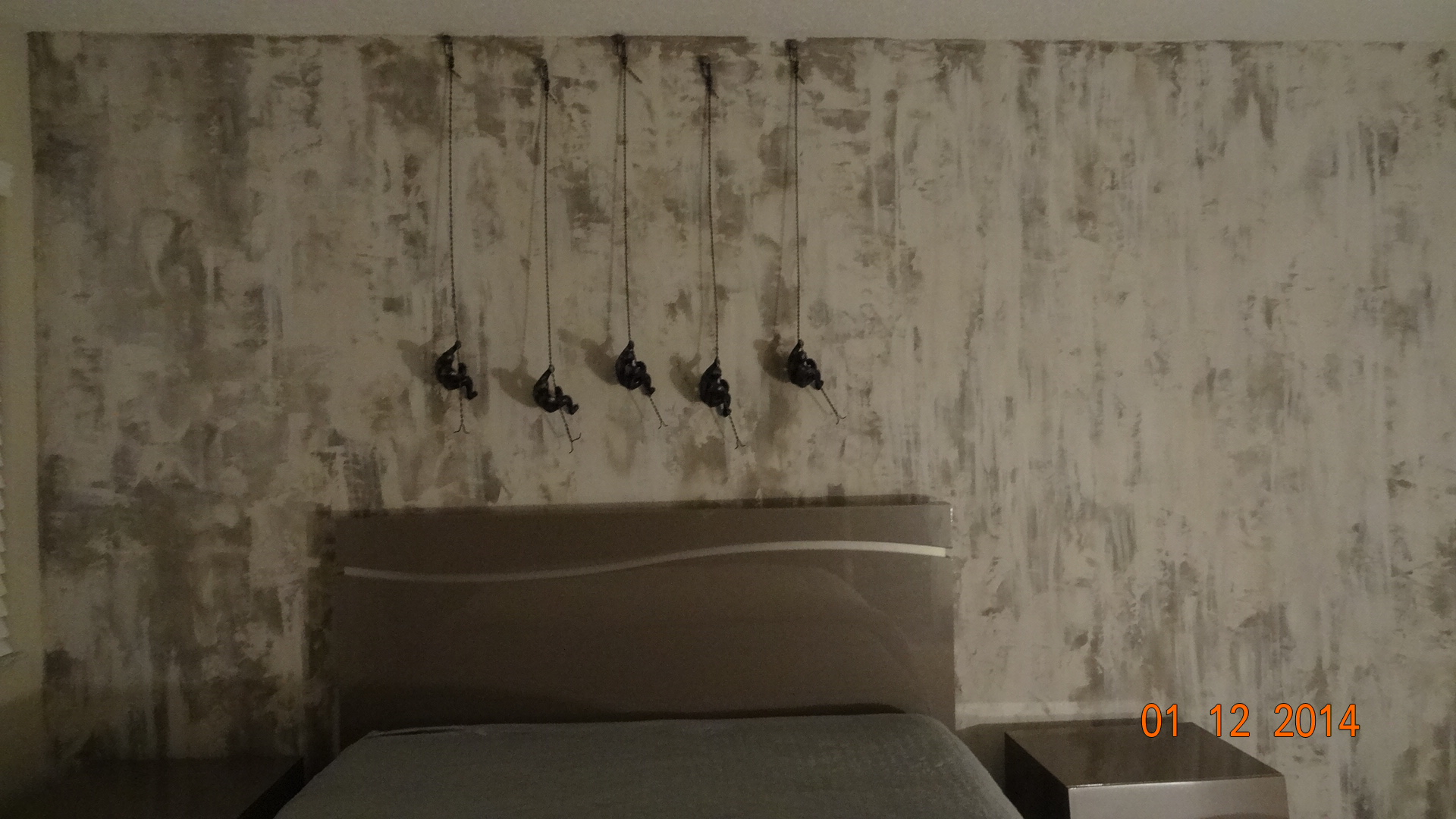 A bed room with a gray headboard and five black lamps hanging from the wall.