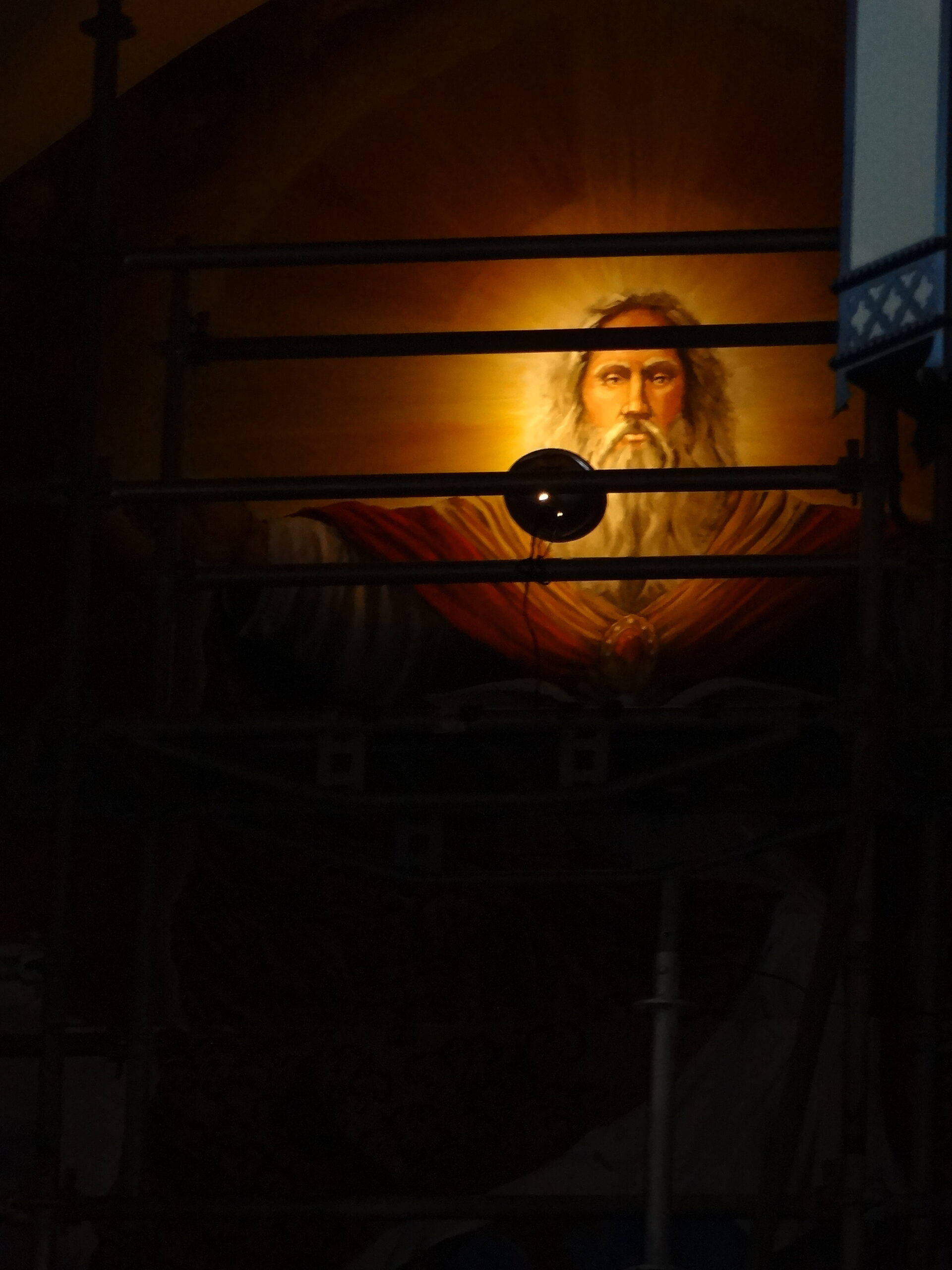 A painting of jesus is seen through the window.