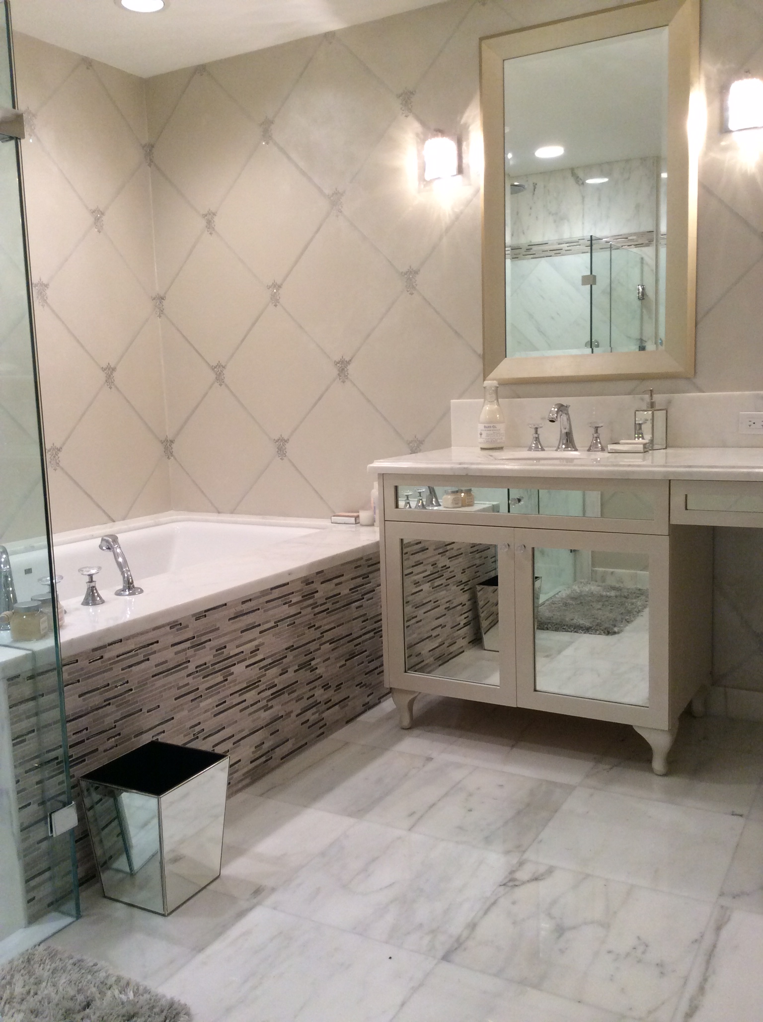 A bathroom with a tub, sink and mirror.