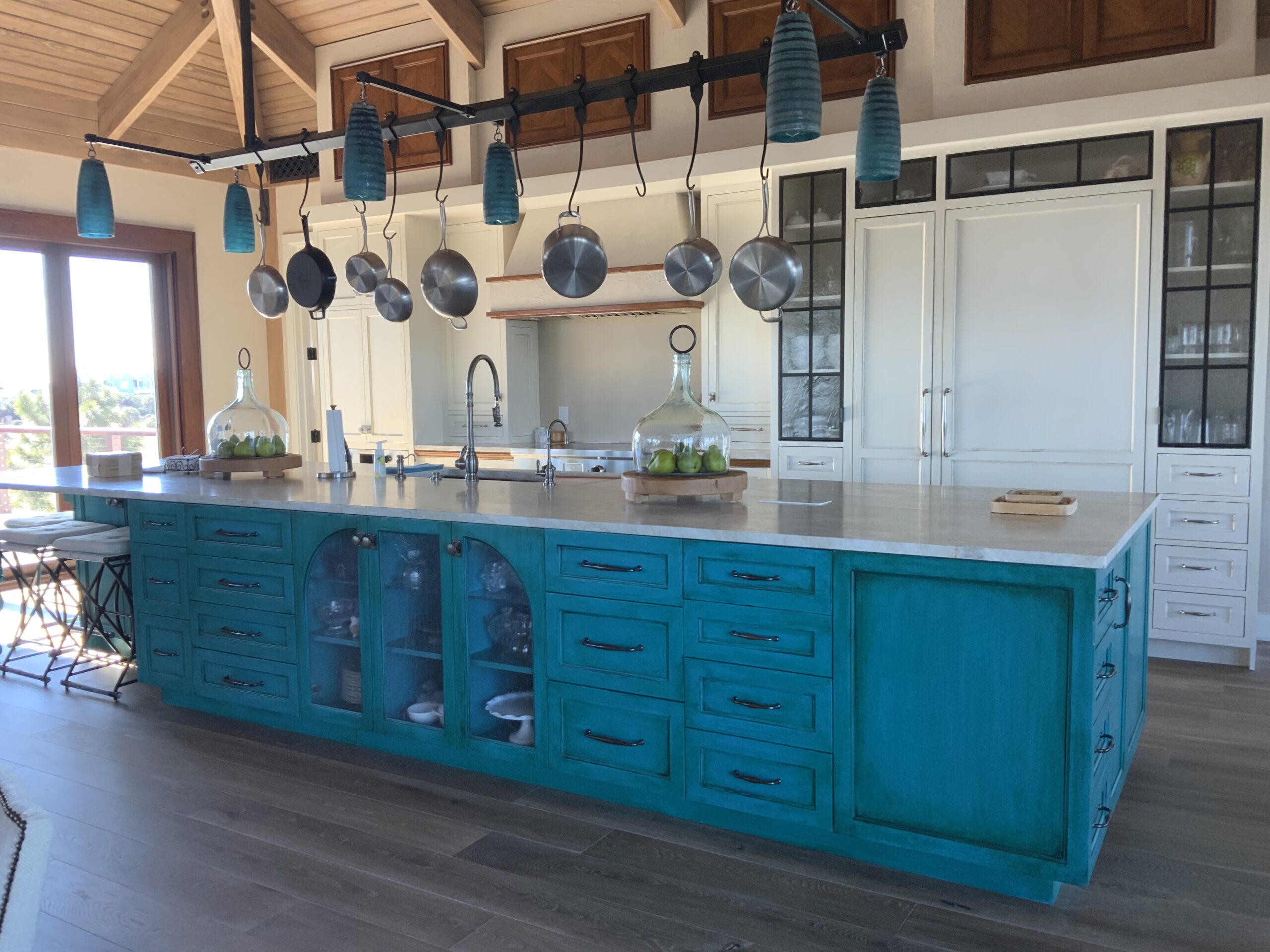 A kitchen with blue cabinets and hanging pots.