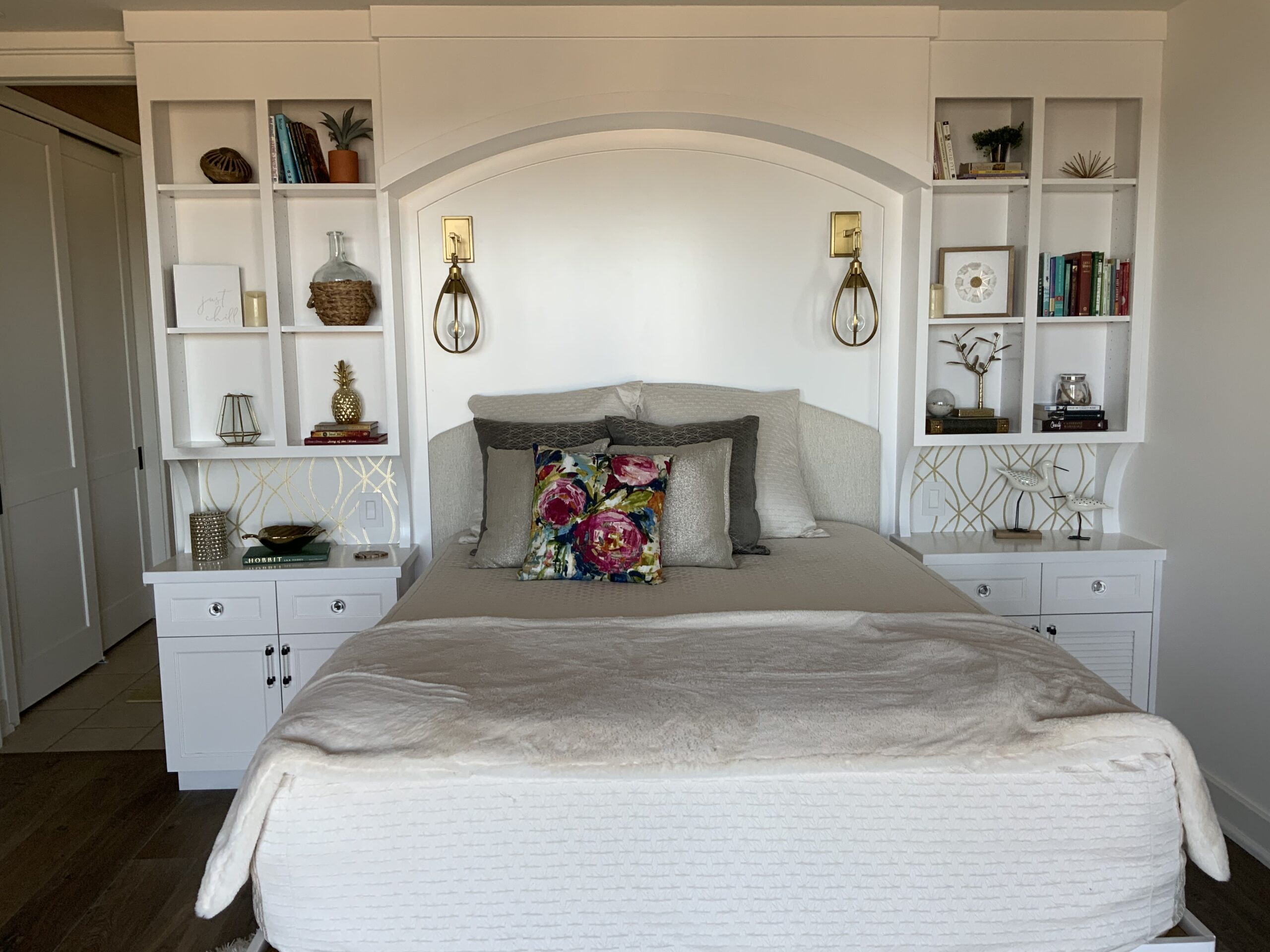 A bed with white walls and shelves in the corner.