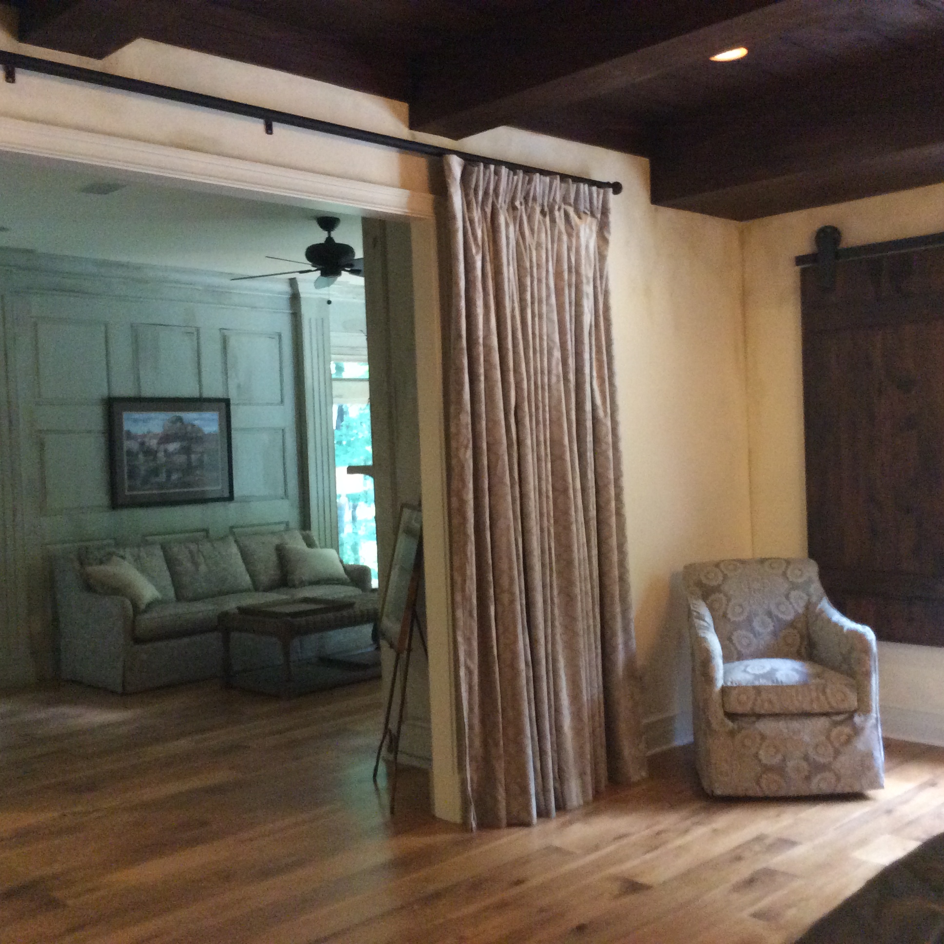 A living room with wood floors and curtains.