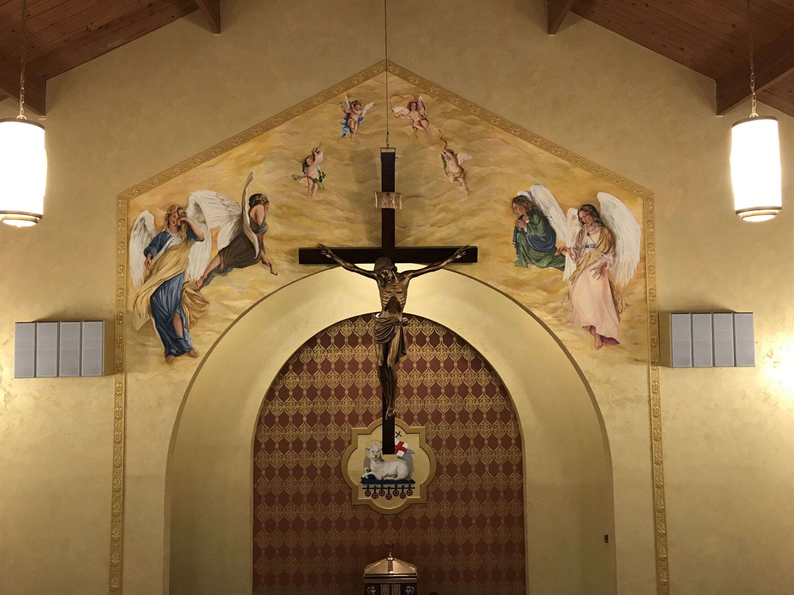 A cross and mural in the center of an archway.