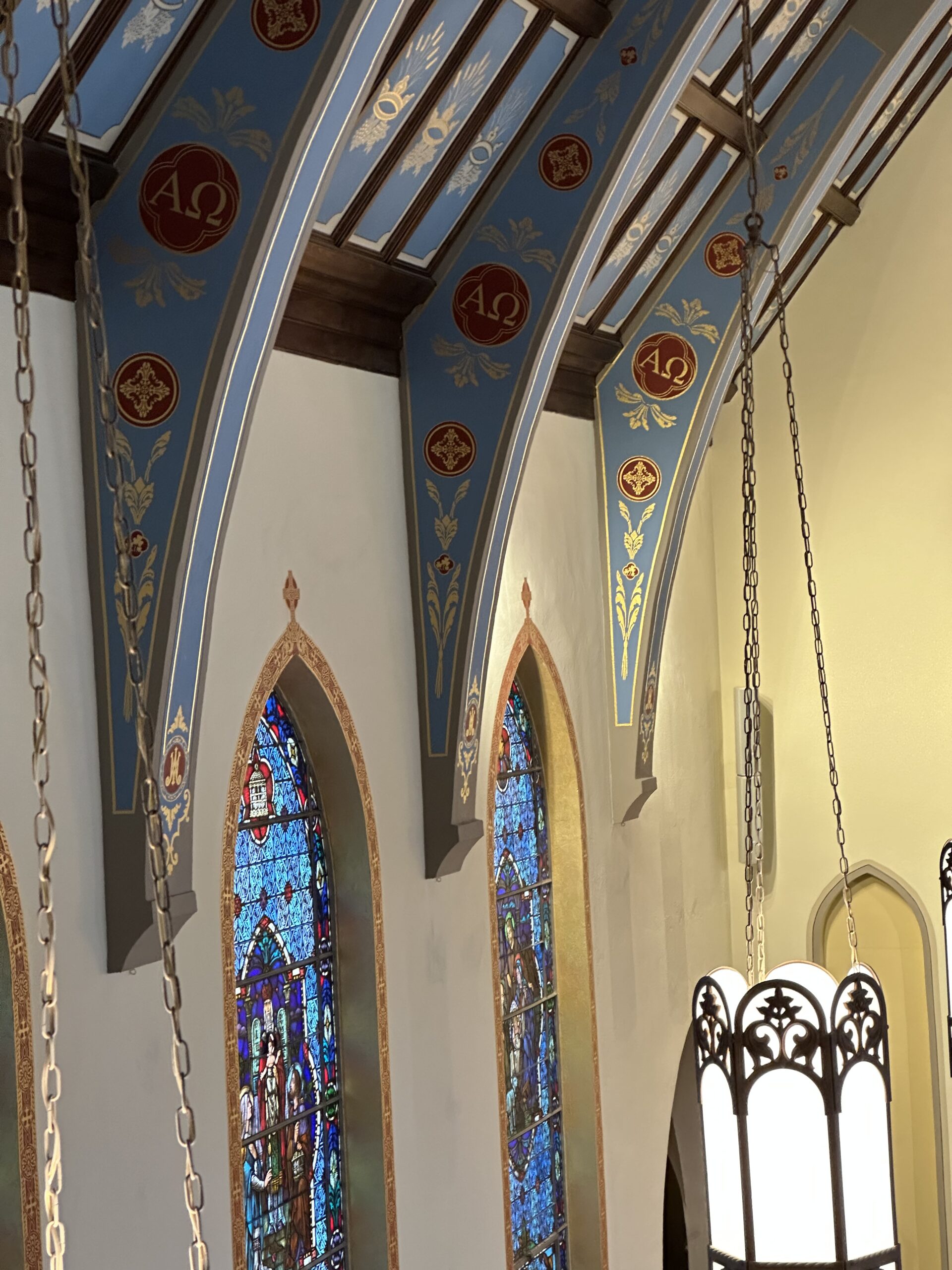 A church with stained glass windows and a chain hanging from the ceiling.