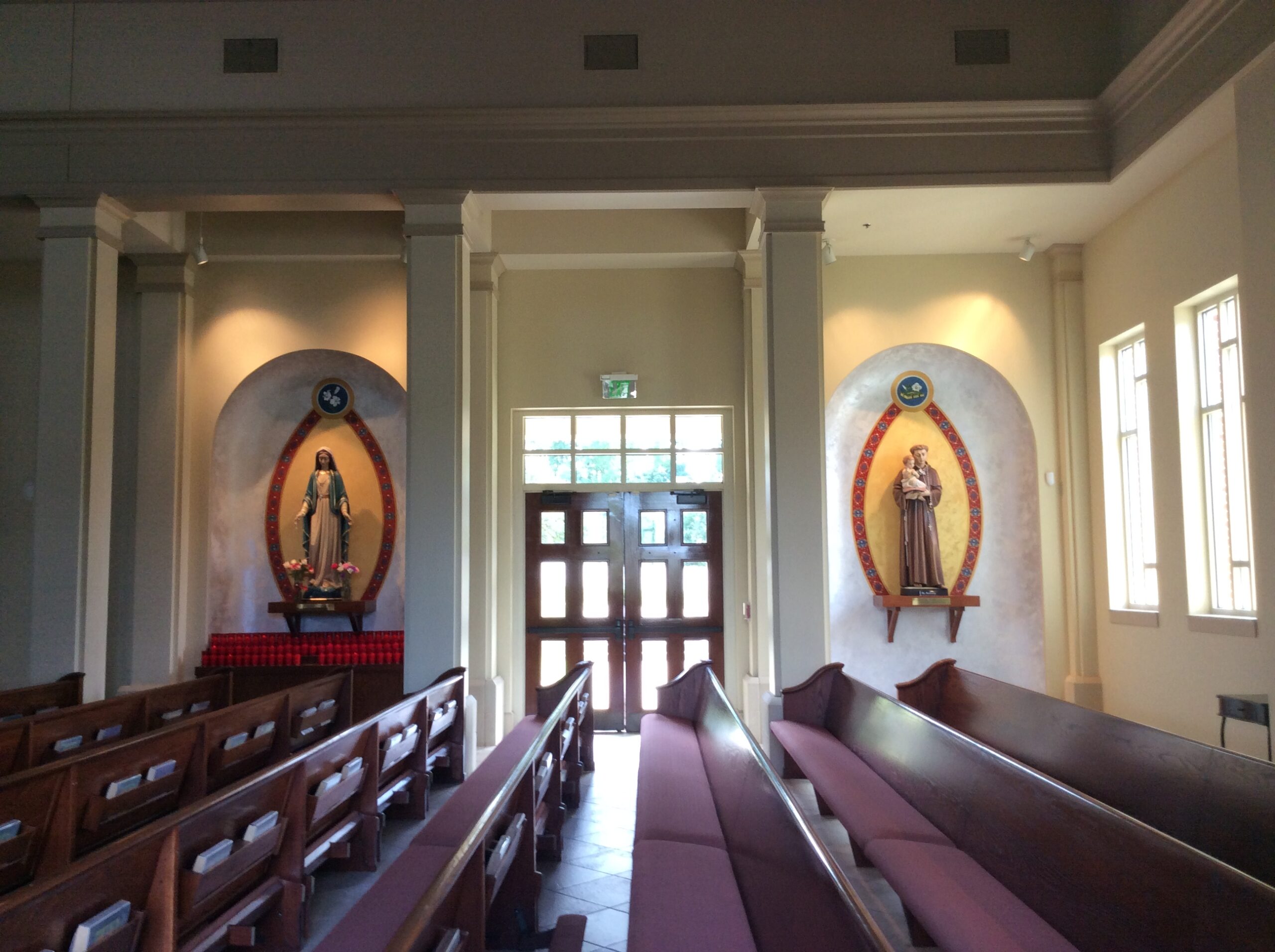 A church with many benches and two paintings on the wall.