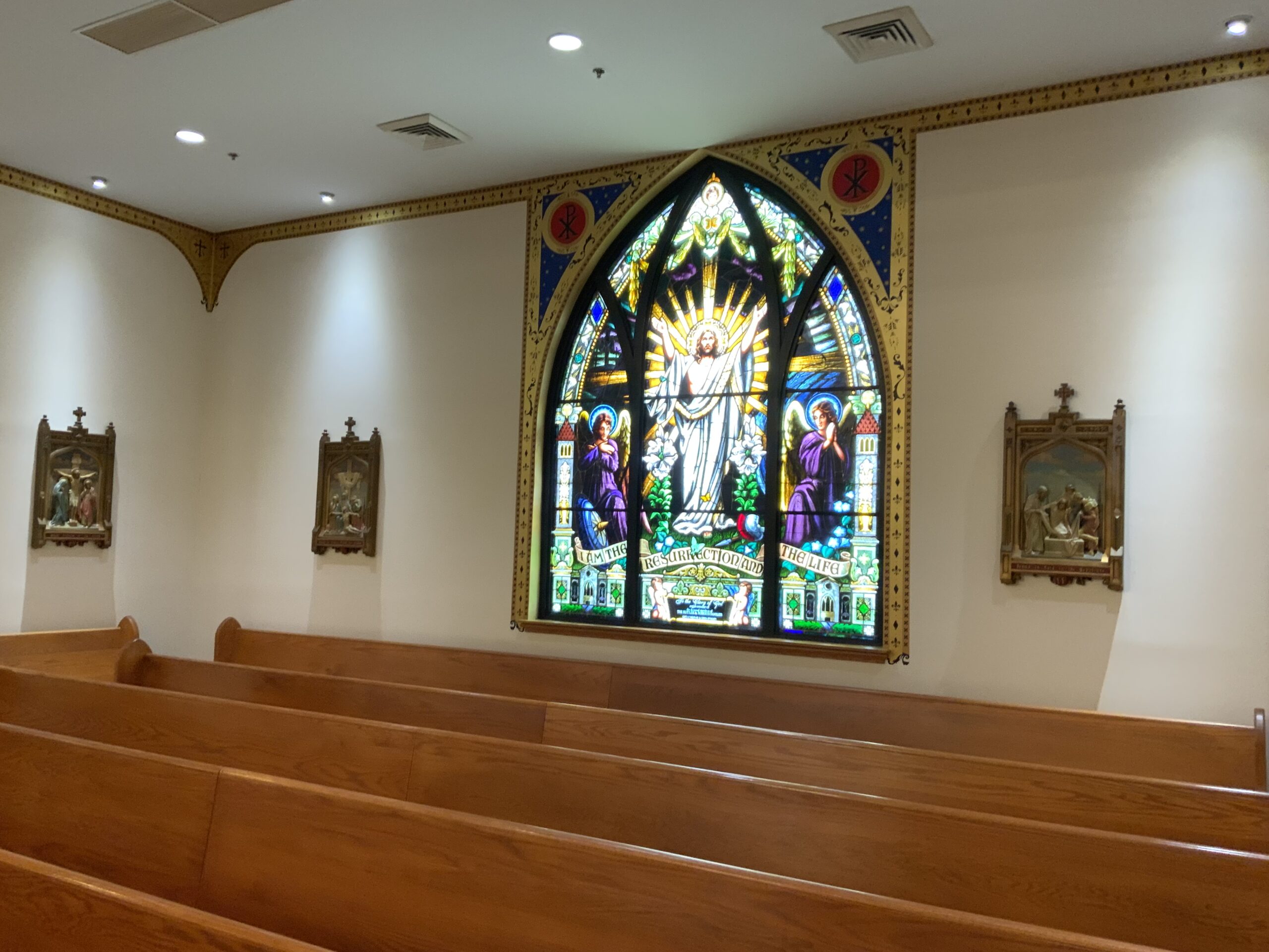 A church with pews and stained glass window.