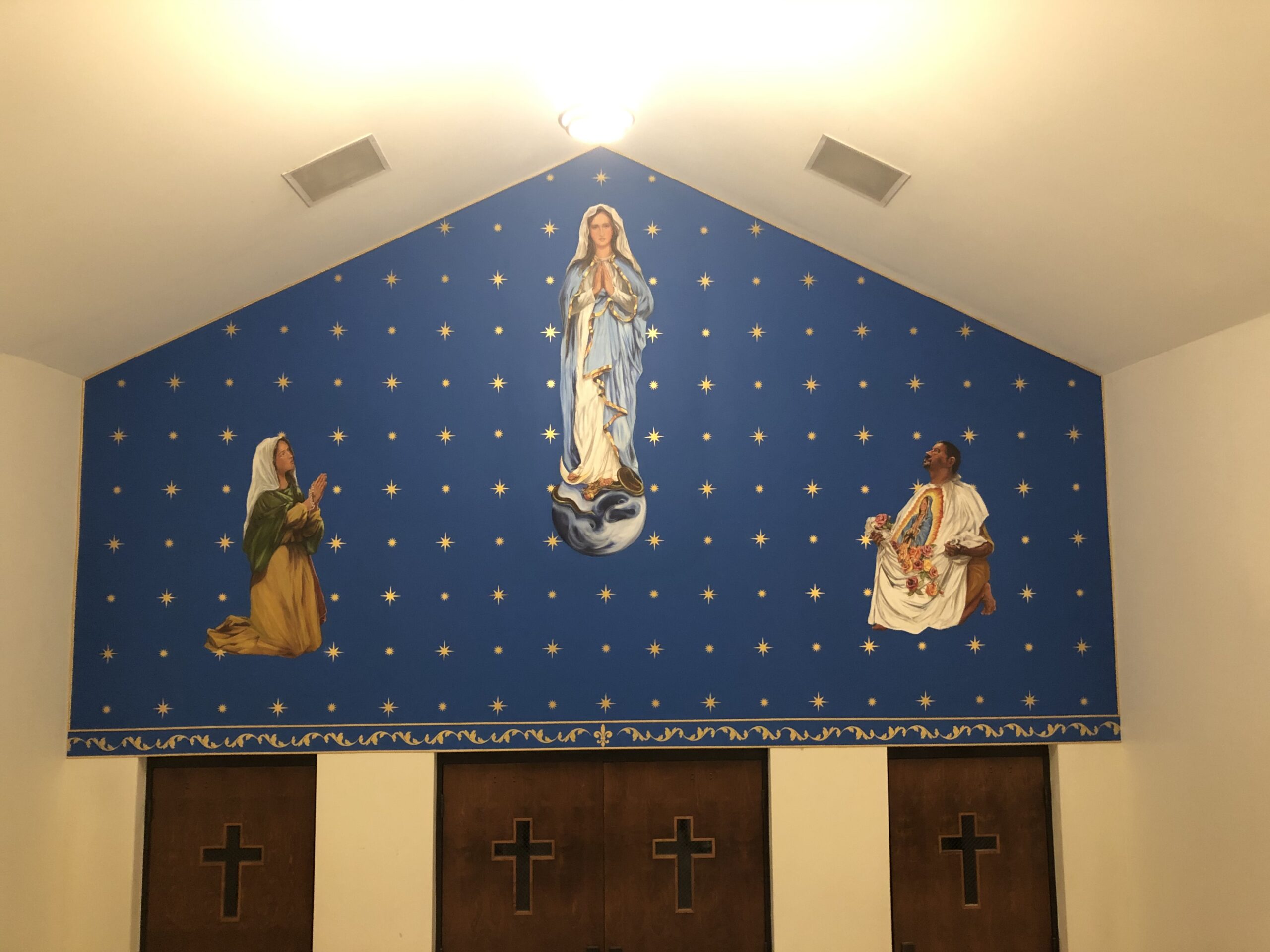 A wall with three pictures of jesus, mary and john.