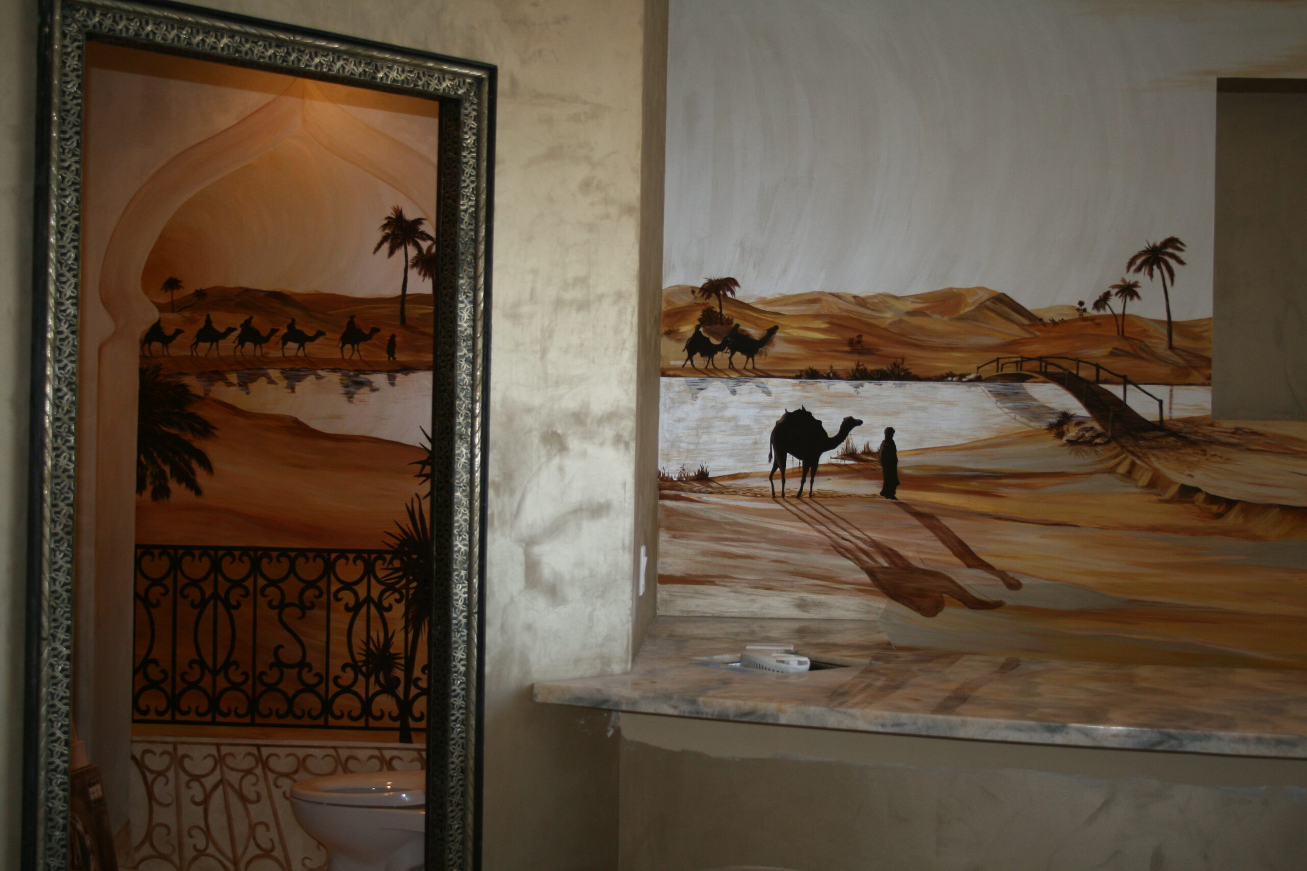 A mirror and wall with an image of a desert scene.