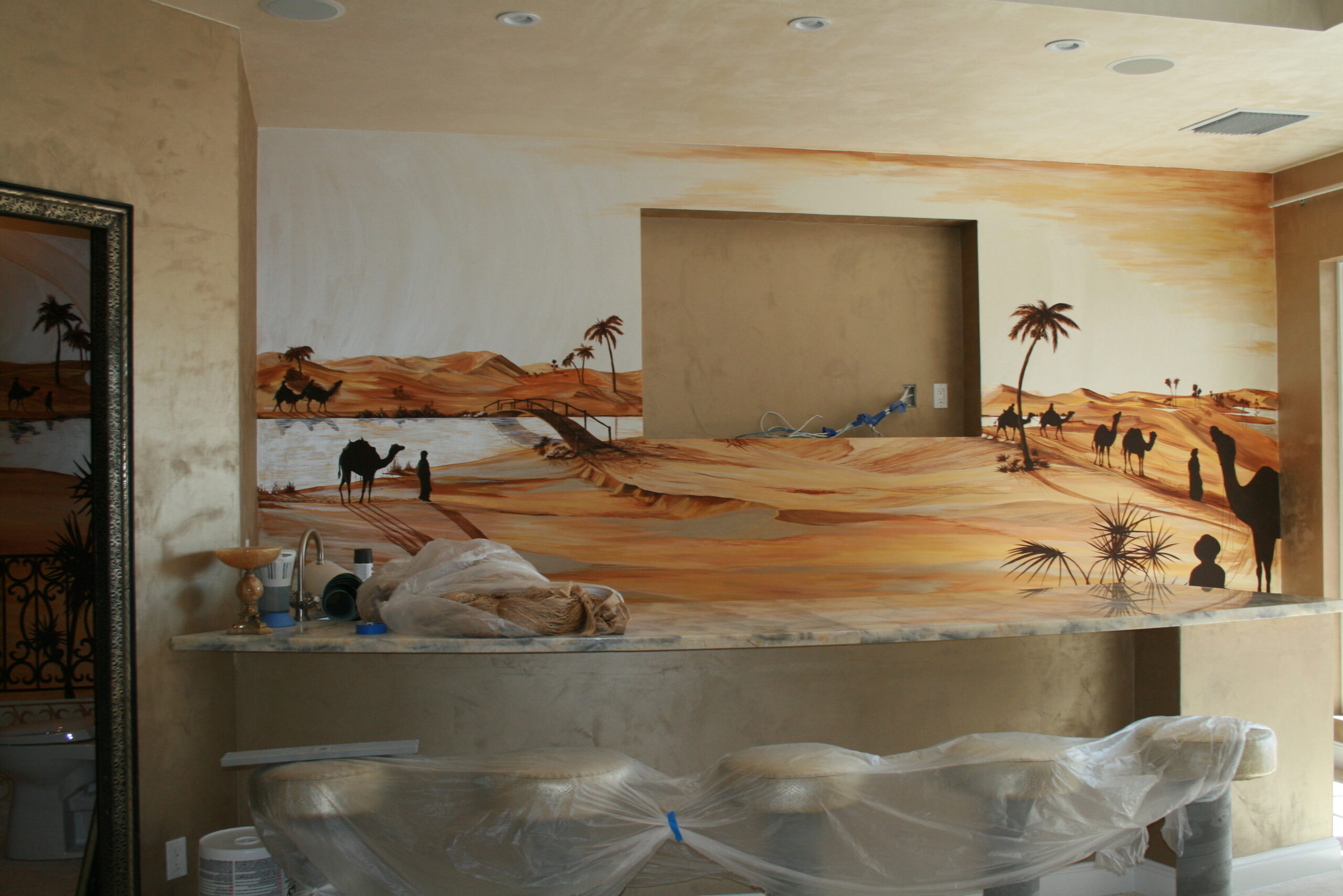 A room with a painting of desert and palm trees.