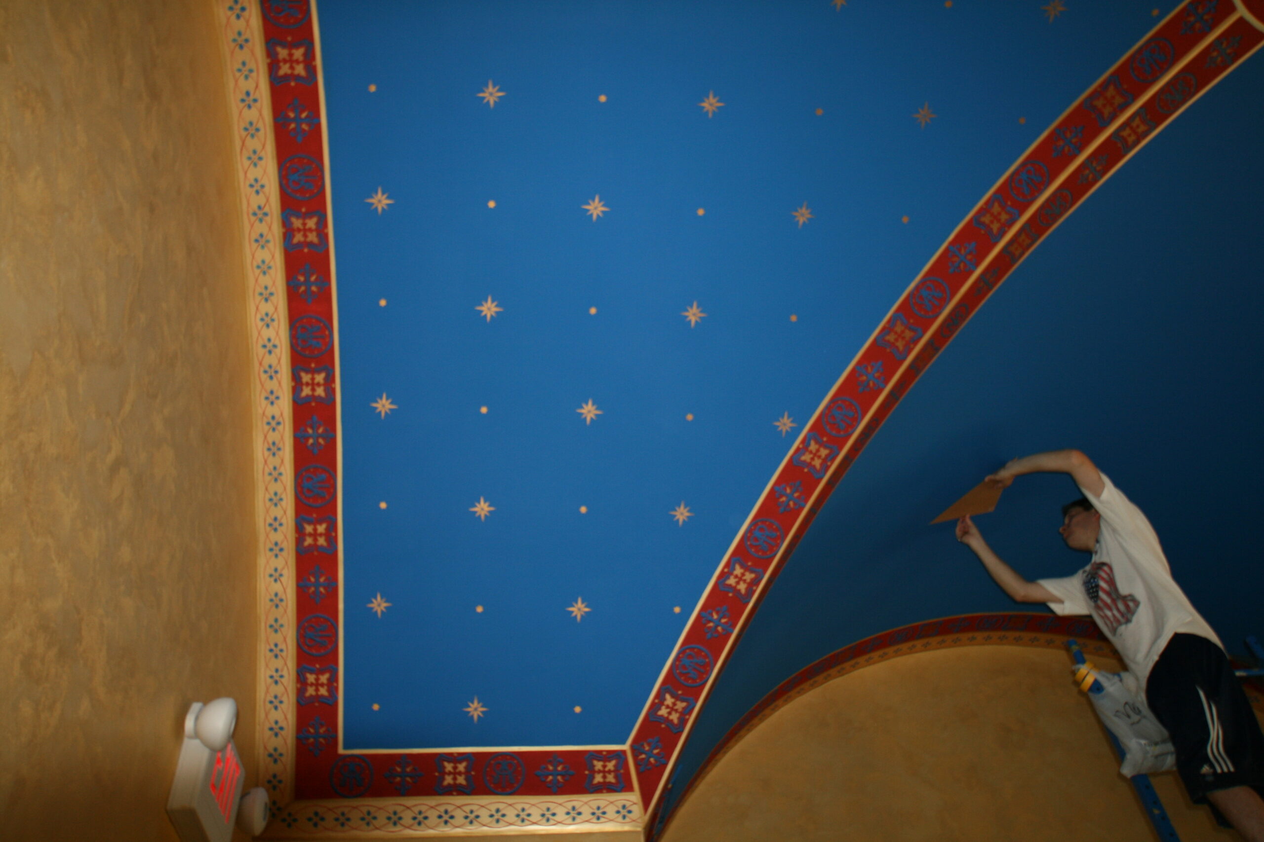 A blue ceiling with red and gold designs on it.